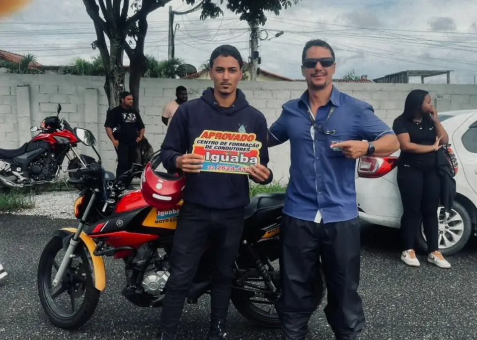 Aluno aprovado na categoria A ao lado da moto da Auto Escola Iguaba e do instrutor