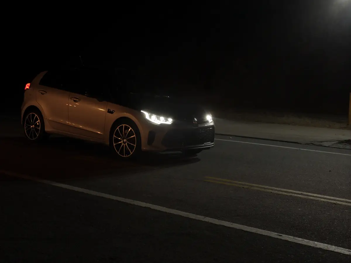 Carro com os faróis acesos numa estrada à noite